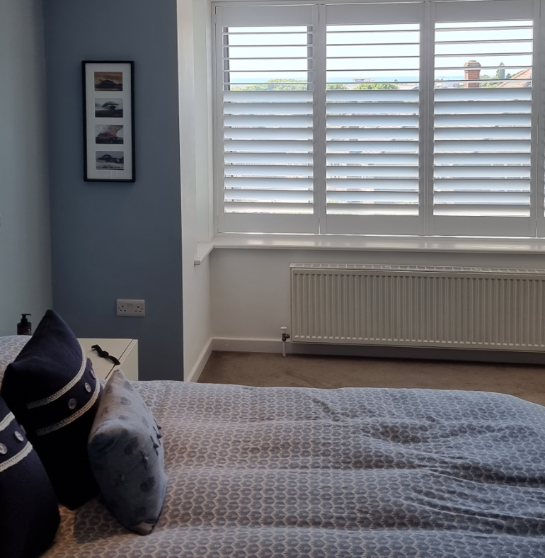 Modern bedroom with plantation shutters on the window, providing a stylish and functional window treatment