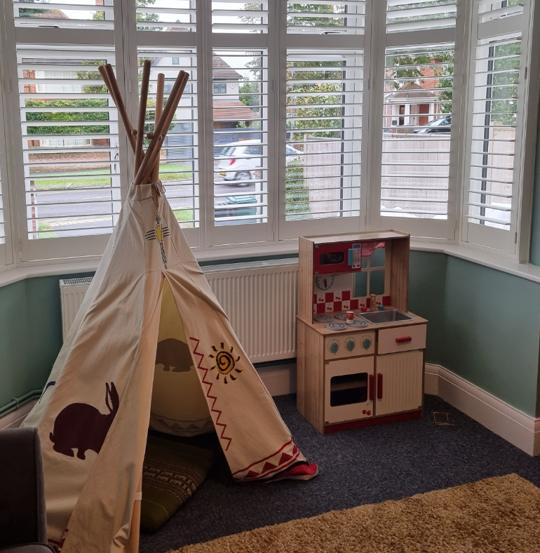 The window is fitted with stylish plantation shutters, allowing natural light to flood the space while adding a touch of modern elegance to the playful and cozy environment